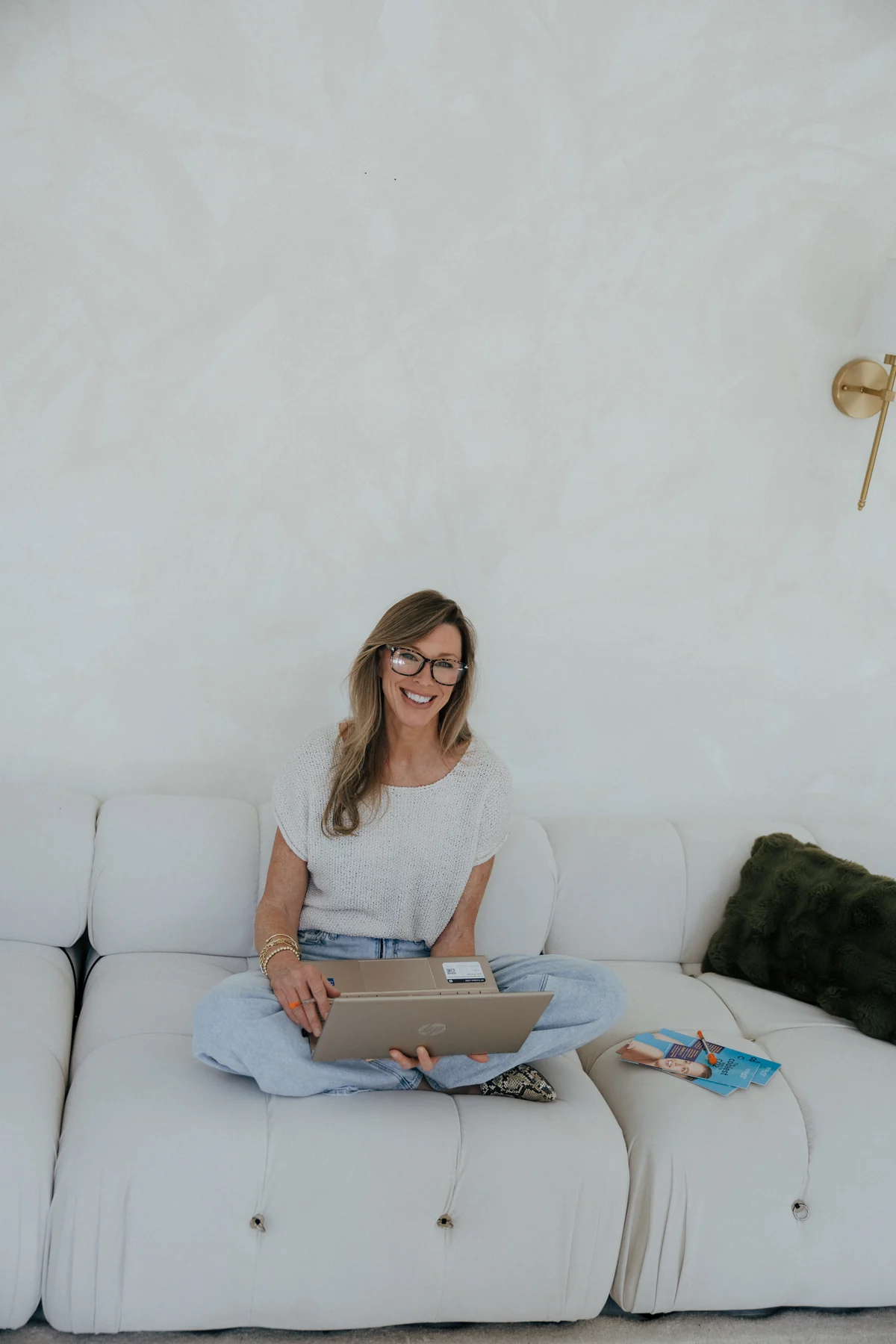 Angie Smith smiling on a couch with her laptop